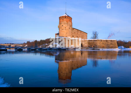 Olavinlinna fortezza nella luce del sole al tramonto su una serata di marzo. Savonlinna, Finlandia Foto Stock