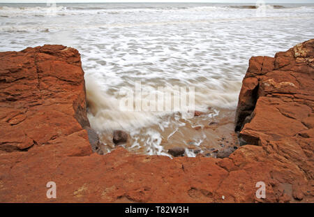 Azione di onda erodendo il più duro di base di argilla di scogliere sulla costa di Norfolk a Happisburgh, Norfolk, Inghilterra, Regno Unito, Europa. Foto Stock