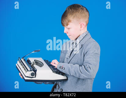 Hes andando a scrivere una composizione. Smart bambino scrittore. Poco scrittore digitazione sul retro della macchina da scrivere. Ragazzo simpatico scrittore lavorando su Mechanical desktop i nastri inchiostratori per macchine da scrivere. Scrittore di piccole dimensioni la composizione di storia. Foto Stock