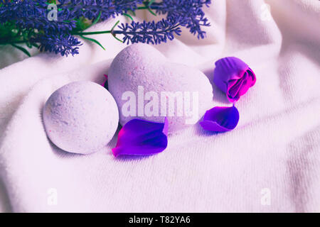 Vasca da bagno bombe a forma di cuore su bianco asciugamano da bagno con lavanda flowes. Foto Stock