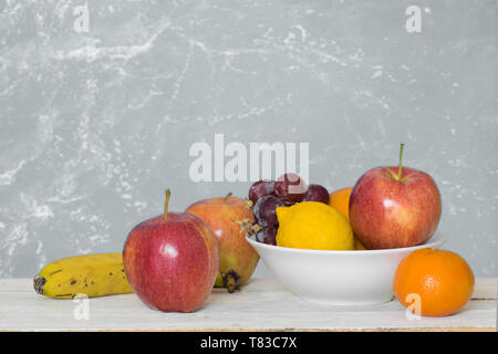 Ancora vita scena con alcuni frutti su un bianco scaffale di legno contro uno sfondo bianco. Svuotare lo spazio di copia per l'editor di testo Foto Stock