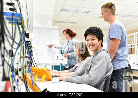 Ritratto di giovani asiatici nella formazione professionale, in background gruppo di apprendisti e di insegnante in classe Foto Stock