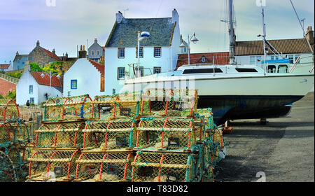 Imbarcazioni di cui fino a terra accanto al cottage tradizionale a Crail Harbour, Fife, Scozia Foto Stock