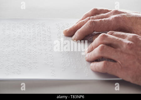 Vista ritagliata della senior uomo la lettura di testo braille isolato su grigio Foto Stock
