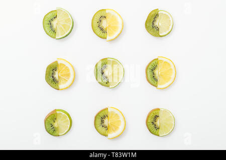 Piatto con laici tagliare i limoni e limette e kiwi sulla superficie bianca Foto Stock