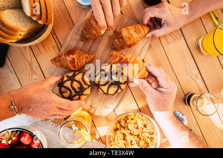 Gruppo di amici famiglia persone visto dalla parte superiore verticale schematica presa croissant e mescolati alimenti per la colazione attività mattutina - tavolo di legno in backgrou Foto Stock