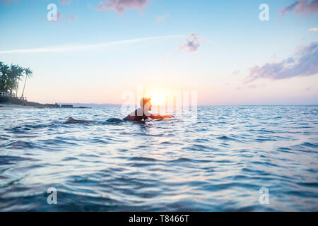 Surfer scorrevolezza in mare al tramonto, Pagudpud, Ilocos Norte, Filippine Foto Stock