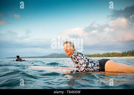 Surfer scorrevolezza in mare al tramonto, Pagudpud, Ilocos Norte, Filippine Foto Stock