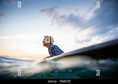 Surfer scorrevolezza in mare al tramonto, Pagudpud, Ilocos Norte, Filippine Foto Stock