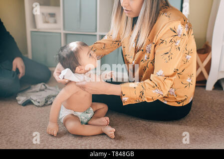 Madre seduta sul pavimento di vivaio medicazione figlio bambino Foto Stock