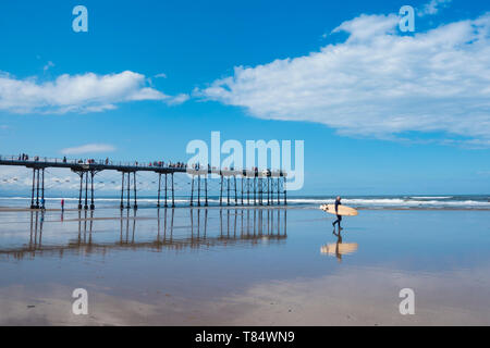 Saltburn dal mare, North Yorkshire, Regno Unito. 11 maggio 2019. Meteo: un surfista capi a Saltburn sulla North Yorkshire coast nel glorioso sole come la città celebra il centocinquantesimo anniversario ot il suo molo vittoriano. Credito: Alan Dawson/Alamy Live News Foto Stock