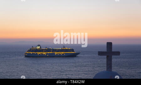 La città di Mykonos, Mykonos, Egeo Meridionale, Grecia. Vista sul mare Egeo dalla collina, crepuscolo, illuminato nave da crociera ancorata al largo. Foto Stock