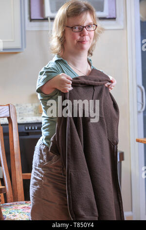 Donna con sindrome di catrame a mettere su la sua camicia Foto Stock