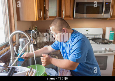 Teen con la sindrome di Down facendo piatti Foto Stock