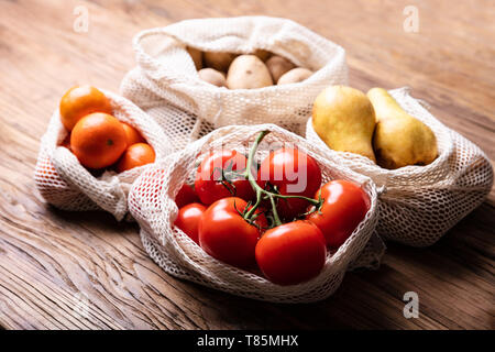 Una vista aerea di verdura e frutta in borsa a rete sulla scrivania in legno Foto Stock