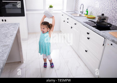 Pretty Girl gettando Piastra bianca in cucina Foto Stock