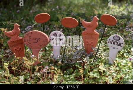 GIARDINO DELLE ERBE AROMATICHE CON MARCATORI DI IDENTIFICAZIONE DELLE PIANTE PER ORIGANO, SALVIA, ERBA, ROSMARINO, ERBACCE, PREZZEMOLO, ERBE MORTE E AGLIO. Foto Stock