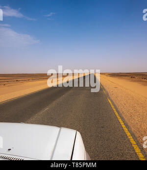 Dritto come una matrice, grigio asfalto attraverso il deserto del Sudan- Foto Stock