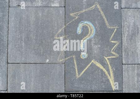 Questione astratta segno disegnato in pastelli su grigio asfalto, vista dall'alto Foto Stock