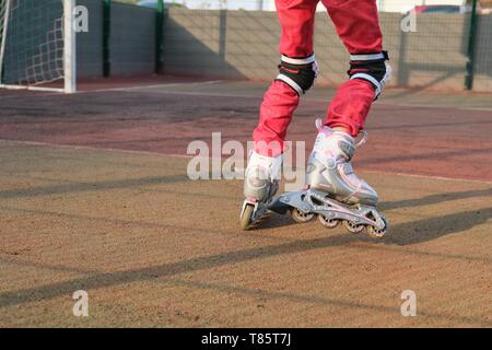 Kiev UA, 21-04-2019. Close-up di piedi calzati figlio di lame a rullo, ragazza attivo a cavallo pattini a rotelle su una speciale area sport vicino alla casa Foto Stock