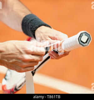Giocatore di mettere un nuovo nastro di presa sulla racchetta da tennis Foto Stock