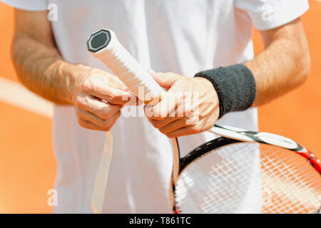 Giocatore di mettere un nuovo nastro di presa sulla racchetta da tennis Foto Stock