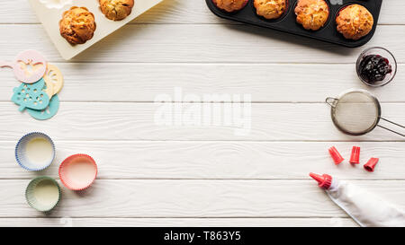 Vista dall'alto di deliziosi muffin e strumenti di cottura su un tavolo di legno con lo spazio di copia Foto Stock