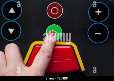 Mano spinge verso il verde 'go' pulsante su un tapis roulant, pronto per essere eseguito Foto Stock