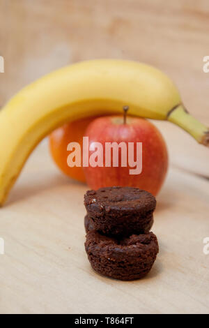 La scelta tra una pila di piccoli brownies o alcuni deliziosi frutti interi Foto Stock