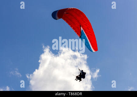 Parapendio in tandem con scivolo rosso galleggiano nuvola bianca Foto Stock