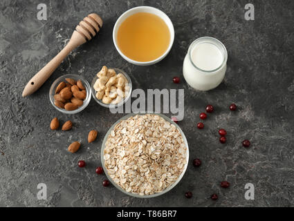 Composizione con fiocchi di avena, dadi, il latte e il miele scuro su sfondo a trama Foto Stock