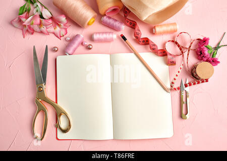 Composizione con notebook, filetti di colori e accessori per il cucito sul colore di sfondo testurizzata Foto Stock