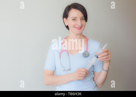 Attraente femmina gentile dottore tenendo la siringa verticale Foto Stock