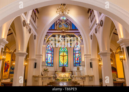 Vista interna della bella chiesa colorati con banchi vuoti e una luce calda. Foto Stock