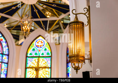 Vista interna della bella chiesa colorati con banchi vuoti e una luce calda. Foto Stock