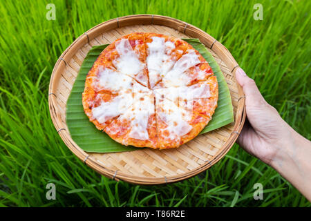 Formaggio sulla pizza tradizionale di bambù piastre di armatura e banana leaf a portata di mano con riso al gelsomino sfondo. Foto Stock