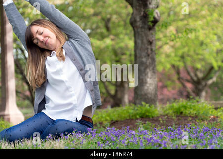 Una millenaria donna seduta in un parco godendo il momento completamente in pace con il mondo e felice della vita Foto Stock