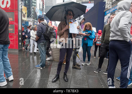 In una piovosa sabato, un attraente giovane donna Vendita discount theatre tickets principalmente per i turisti. Times Square Manhattan, New York City. Foto Stock