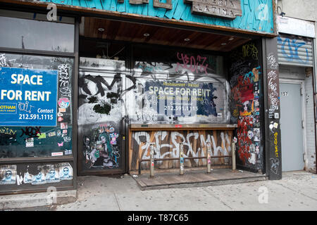 Un vacante store per noleggiare sulla Houston Street a Manhattan coperto di graffiti, adesivi ed etichette. Lower East Side di New York City. Foto Stock