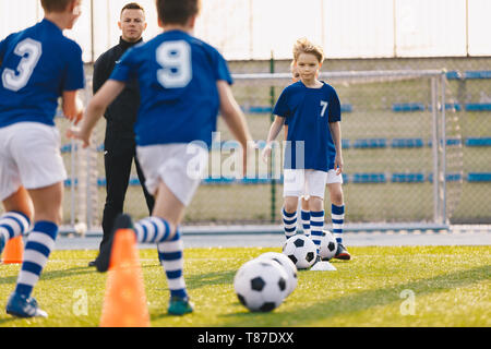 I bambini la formazione di calcio. I ragazzi in esecuzione con la sfera sulla Formazione Pratica Sessione. Happy Boys Sport e divertimento all'aperto Foto Stock