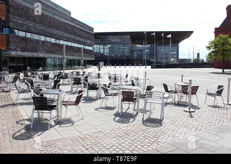 10 Maggio 2019: la Baia di Cardiff, Cardiff Regno Unito: Set di sedie sedervi al sole accanto al Wales Millennium Centre e National Assembly for Wales. Foto Stock