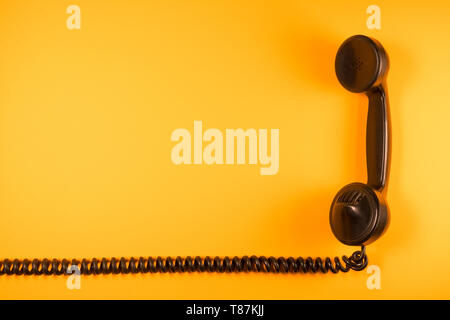 Il vecchio telefono del primo novecento isolato con il suo elastico cavo a spirale sul folle colore di sfondo Foto Stock