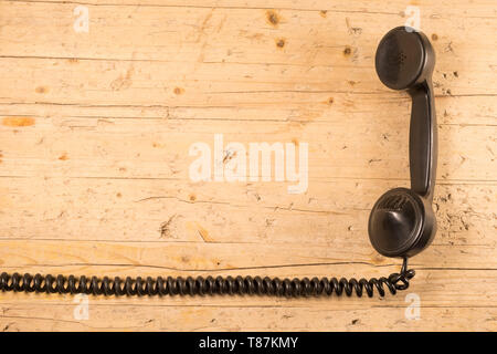 Il vecchio telefono del primo novecento isolato con il suo elastico cavo ritorto sul vecchio sfondo di legno Foto Stock