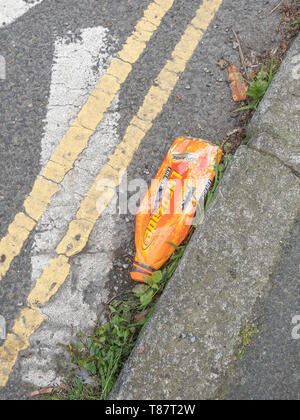 Svuotare la bottiglia di plastica giacente in street grondaia. Rifiuti di plastica / guerra sulla plastica metafore, rifiuti plastici, spazzatura in strada, l'imballaggio di alimenti spazzatura. Foto Stock