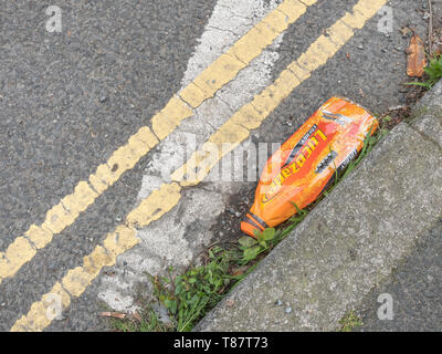 Svuotare la bottiglia di plastica giacente in street grondaia. Rifiuti di plastica / guerra sulla plastica metafore, rifiuti plastici, spazzatura in strada, l'imballaggio di alimenti spazzatura. Foto Stock