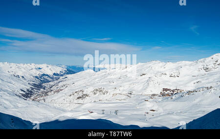 Vista panoramica verso il basso coperto di neve valle nella catena montuosa alpina con ski resort village Foto Stock