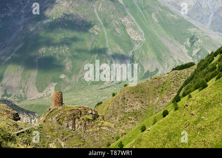 La vista sulla torre di difesa sulla rotta di Tsminda Sameba la Chiesa georgiana si trova sulla verde collina sopra la città Stepantsminda. Foto Stock