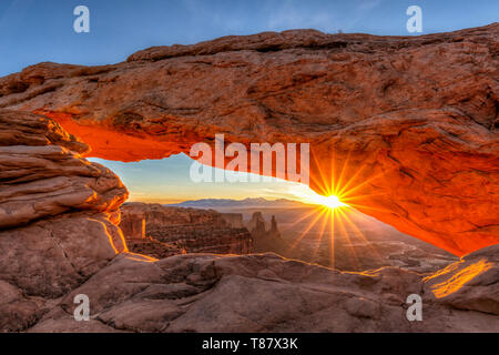 Un sunburst picchi fuori attraverso Mesa Arch nel Parco Nazionale di Canyonlands, Utah Foto Stock