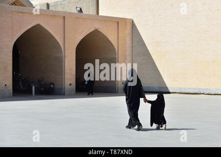 Madre musulmano con la figlia con il tradizionale chador è percorrendo strade nella città di Isfahan, Iran. Foto Stock