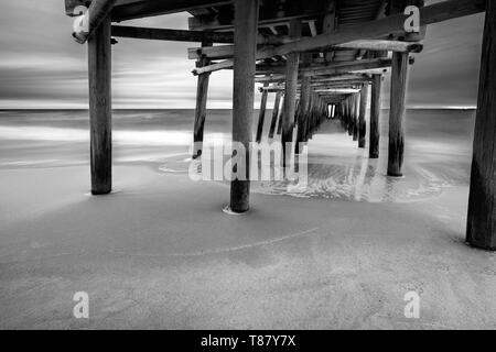 Come il sole sorge dietro la pesca Sandbridge Pier, onde crash - sotto-temi: prospettica, pace lunga esposizione, Otturatore lento, misty Foto Stock